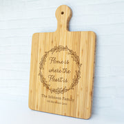 a cutting board with the words home is where the heart is