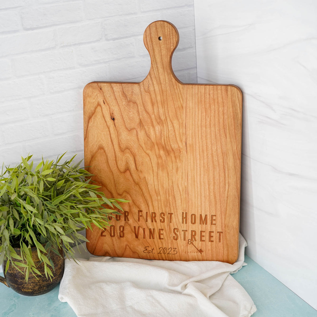 a wooden cutting board sitting next to a potted plant