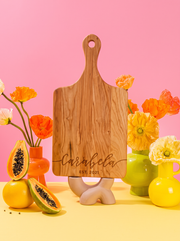 Flowing Script Family Name Cutting Board in a colorful floral setting