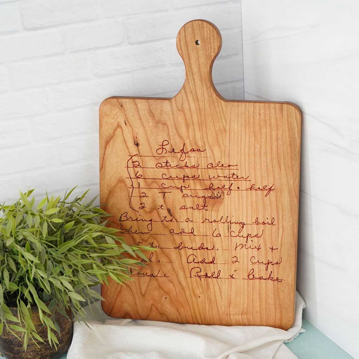 a cutting board with writing on it next to a potted plant