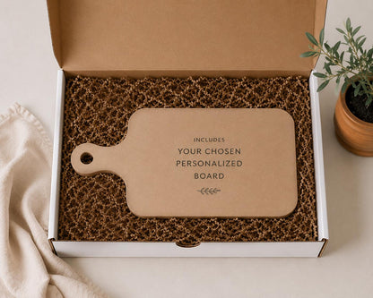 a cardboard box containing a wooden cutting board, with a potted plant and a cloth visible in the background.