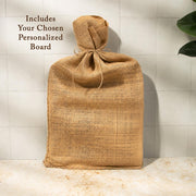 A burlap sack tied with a string, placed on a white tiled surface against a white wall.