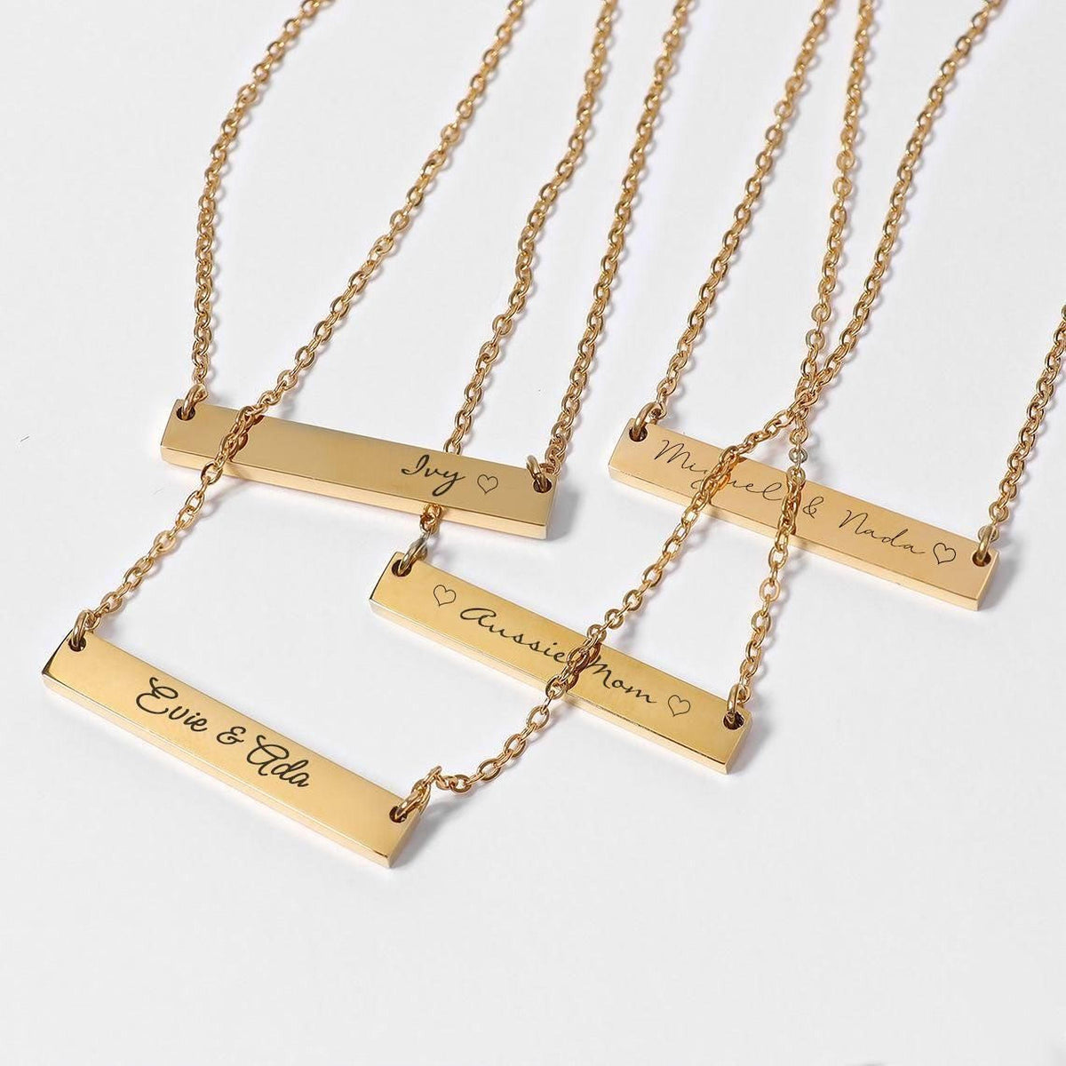 a collection of gold-colored metal necklaces with personalized engraved names on them.