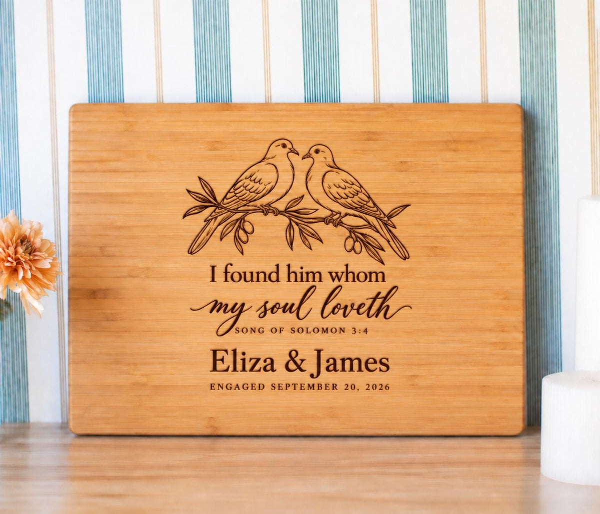 Edited mockup of paired doves, Song of Solomon 3:4, names and engagement date on a rectangular bamboo cutting board.