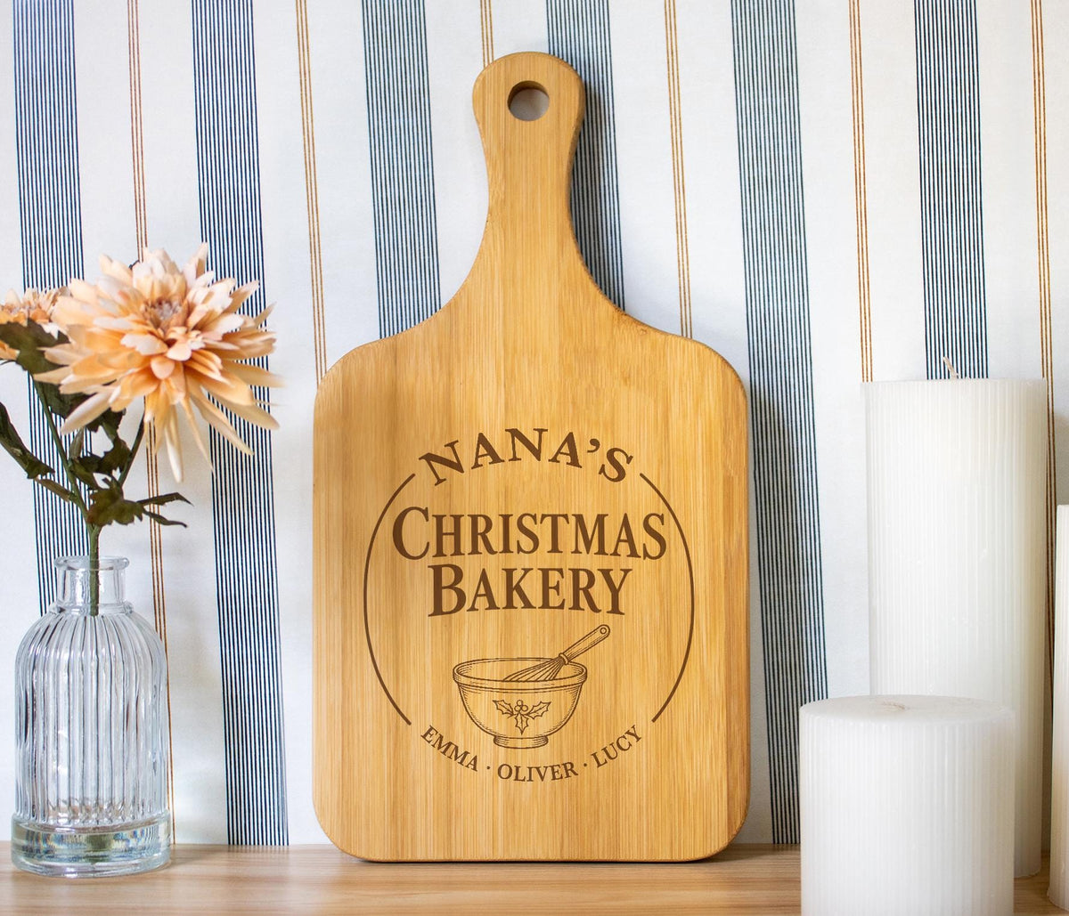 Holly Mixing Bowl edited mockup on a bamboo handled board, with Christmas Bakery lettering and grandkids’ names beside a flower vase and white candles.