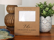I Do frame mockup beside a lamp and a potted plant, with an empty photo opening. THE DAY WE SAID above the opening; I do, Charlotte & James and 14 June 2026 below.