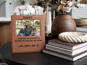 Edited mockup of the tall we grow Daddy frame beside books and a vase, with a sample dad-and-children photo, engraved saying, Love, Emma & Jack signature and outline heart.