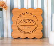 Edited mockup of a cherry square scalloped board with Emma’s Sourdough Bakery loaf emblem and EST. 2020.
