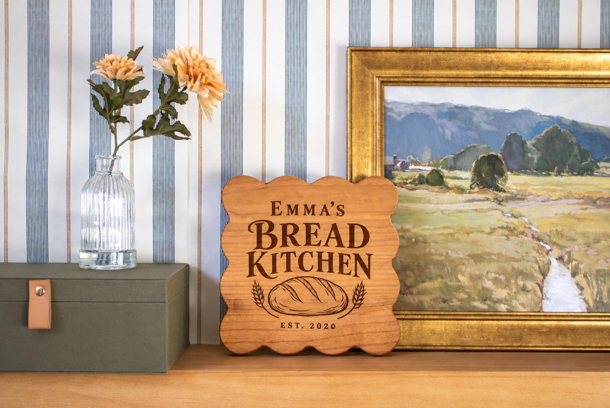 Generated engraving mockup of Emma’s Bread Kitchen with loaf, wheat and EST. 2020 on a cherry square scalloped board.