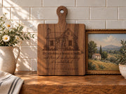 Edited mockup of a handled board with Proverbs Garden House engraving beside flowers and a framed landscape.