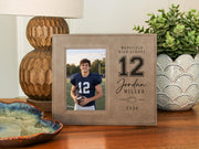 Varsity Football frame mockup beside a lamp, with a portrait football player photo and sample Westfield High School, number 12, Jordan Miller, and 2026 engraving.