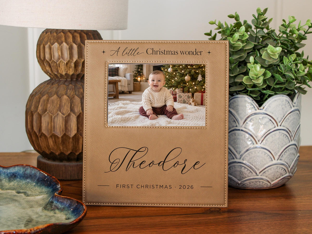 Edited mockup of Christmas Wonder frame with star-accented headline, Theodore and First Christmas 2026, and an illustrative baby photo beside a lamp and plant.