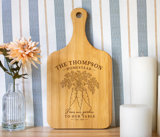 Edited Homestead Carrots mockup on a light bamboo paddle board with carrot engraving and sample Thompson Homestead personalization.