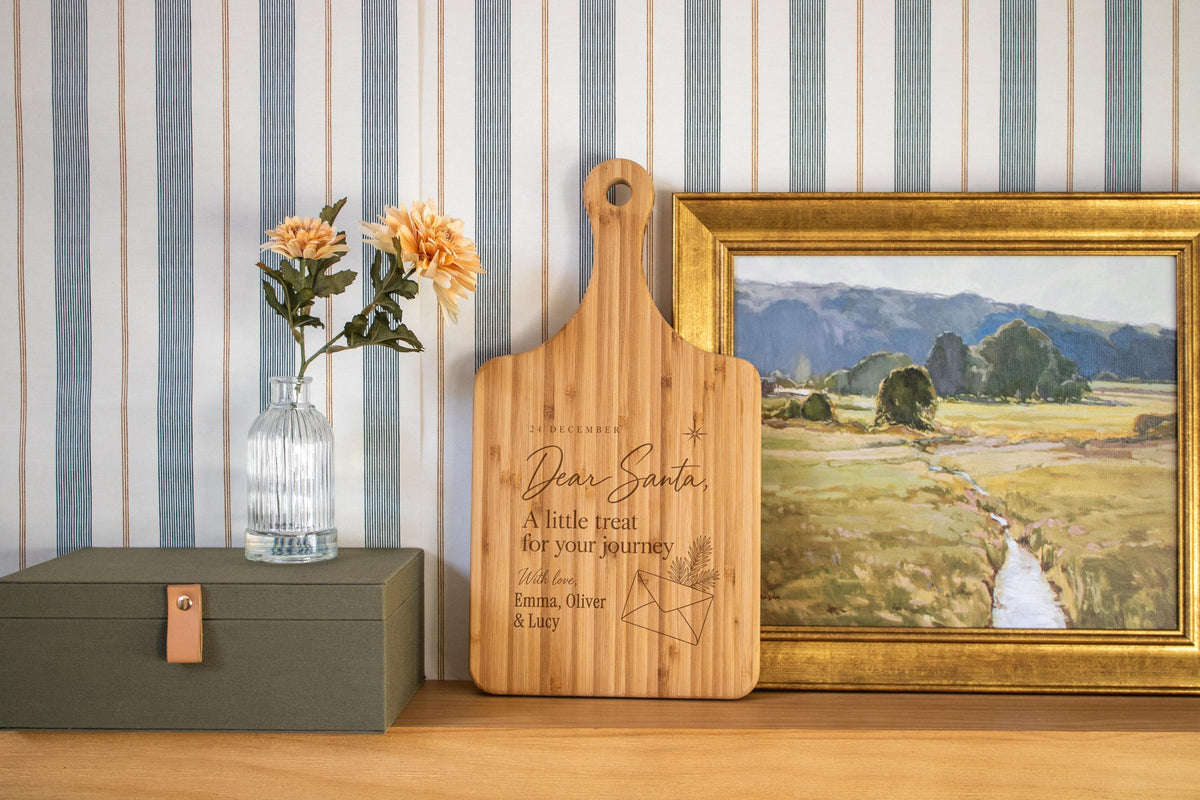Personalized Dear Santa cutting board with letter, evergreen envelope and children’s names in a styled kitchen scene.